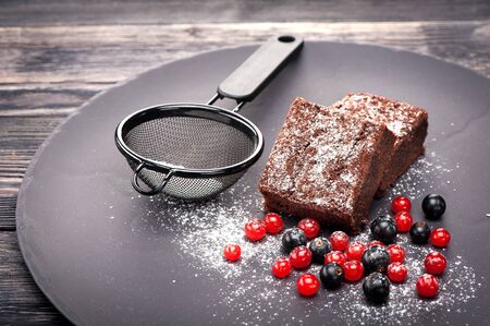 Chocolate brownie with berries and icing sugar