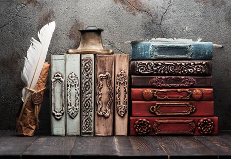Vintage books on a wooden shelf,  paper scroll with a wax seal,
iinkwell and feather for writing. Retro still lifeの写真素材
