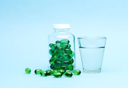 Medical capsules tablets and glass water on a blue backgroundの写真素材