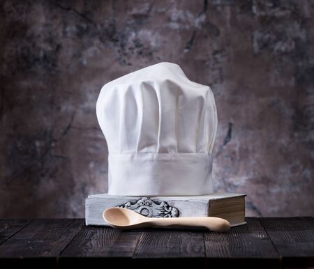 Chef hat, cookbook and wooden spoons on a wooden table.
Cooking still lifeの写真素材