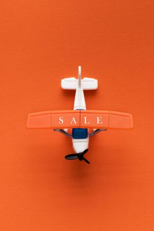 Miniature airplane with the inscription sale on an orange background. Discount and sale concept