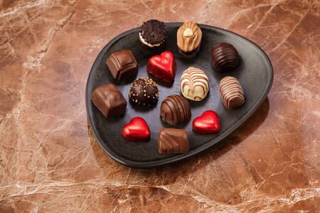 Chocolate candies and cakes on a plate on a marble table, top viewの写真素材