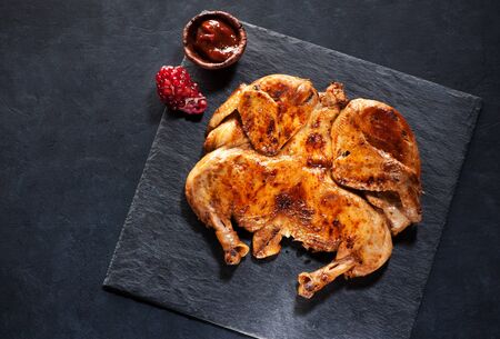 Grilled fried roast Chicken Tabaka on a black chalkboardの写真素材