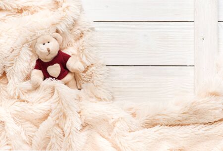 Small knitted baby toy bear is covered with a warm blanket, flat lay, top viewの写真素材