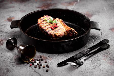 Grilled beef steak in a cast-iron frying pan on a concrete backgroundの写真素材