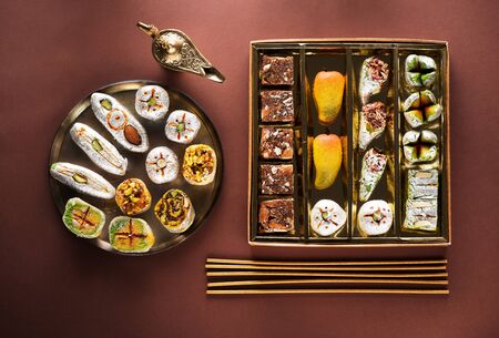 Indian sweets and Mithai in a box and a plate, insense sticks and Aladdin lamp. Diwali festival concept, flat lay, top viewの写真素材