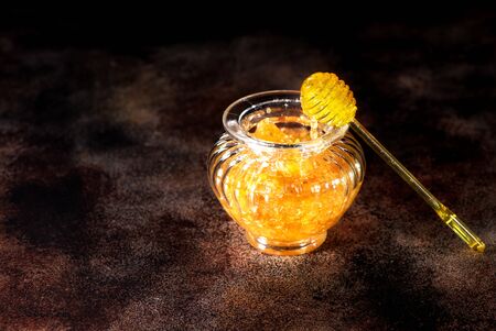 Honey comb in a glass jar and a spoon for honeyの写真素材