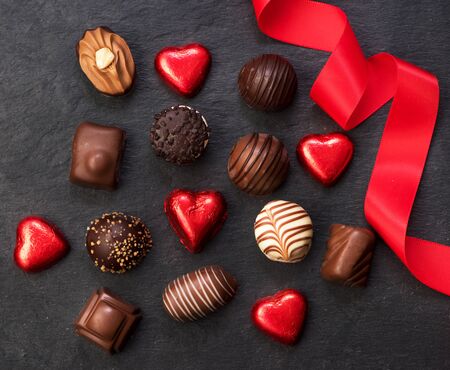 Various chocolate candies and a red ribbonの写真素材
