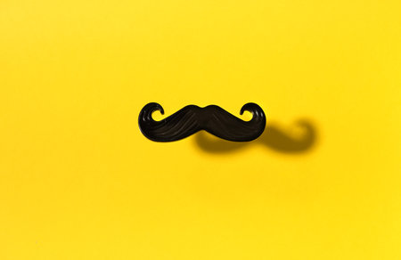 Fake black mustache on yellow background, top view copy spaceの写真素材