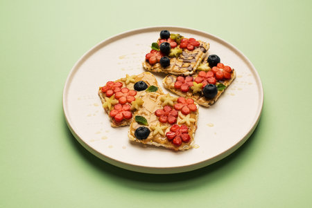 Delicious diet breakfast cereal sandwiches with peanut butter with fruits and berries on a plate, top view. Healthy food conceptの写真素材