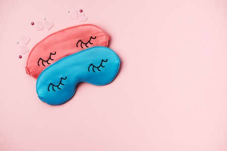 Pink and blue sleeping eye masks on pink paper background, copy space. Top view, flat lay. Concept relaxation and sweet dreamsの写真素材