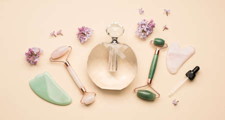 Beauty gadgets. Facial Rollers and guasha scrapers for facial massage on a light beige background. Flat lay, top view. Massage tools for face careの写真素材