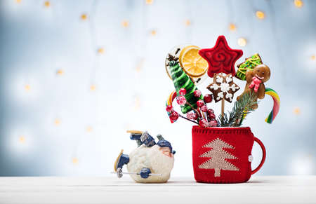 Christmas or New Year card with Christmas gingerbread and candy and Santa Claus on wooden background. Festive decorations and presents for winter holidays.
