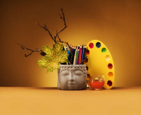Still life from the Head of Buddha. Colored watercolor pencils and palette for paints. A set for...