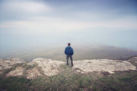 Man in fog in mountain looking to infinity. Conceptual scene.