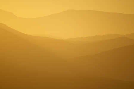 Colorful summer morning layers of mountain with golden light and fog.