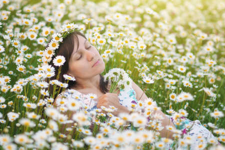 Young woman in chamomile meadow. Nature composition.の写真素材