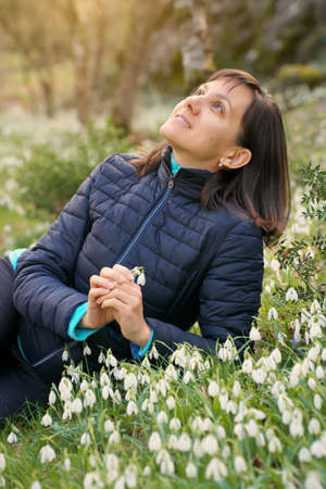 Young woman rest in field of snowdrops. Nature and relax scene.の写真素材