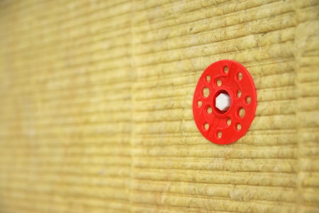 Green mineral wool are attached to the wall with dowels with red plastic caps. Construction and building process.の写真素材