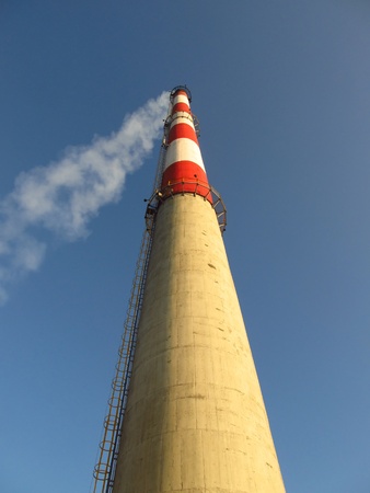high white-red chimney against a blue cloudless sky