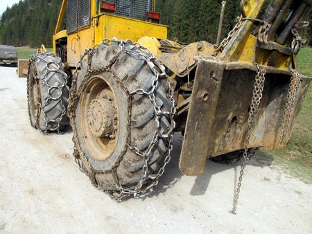 Closeup of wheels of the tractor chain forest in the mountains