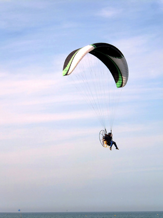 Para glider flying along the coast at the serene sky