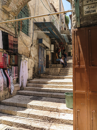 JERUSALEM, ISRAEL - JULY 13, 2015: Narrow stone street among stalls with traditional souvenirs and goods at bazaar in Old City - popular place among tourists and pilgrims visiting Jerusalem.のeditorial素材