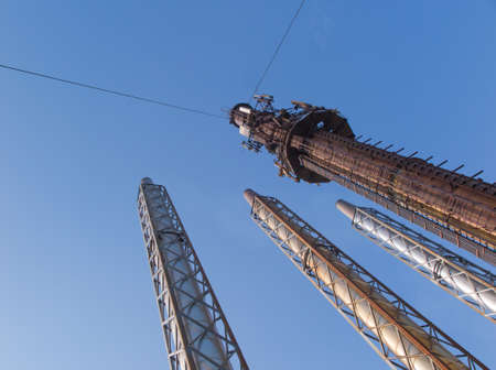 four steel chimneys on a background of blue sky, three new and one oldの写真素材