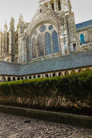 View of famous Le Mont Saint-Michel tidal island on a sunny day with blue sky and clouds, Normandy, northern France. Old concrete cross.のeditorial素材