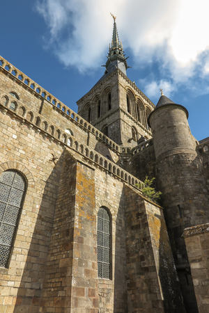 View of famous Le Mont Saint-Michel tidal island on a sunny day with blue sky and clouds, Normandy, northern France. Old concrete cross.のeditorial素材