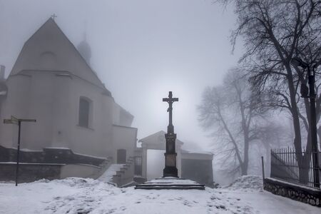 Old cross in front of the entrance to the International Shrine of St. Anna, the winter fog. Mount St. Anna,の写真素材