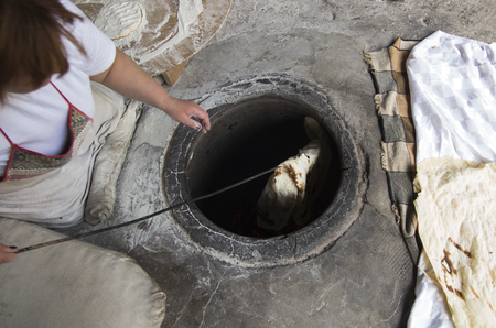 Baking traditional lavash in the tandoor or in a clay oven buried in the floor.の写真素材