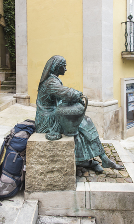 Coimbra, PORTUGAL - JUNE 11, 2018: Statue of a woman sitting with a water jug on a street in Coimbra, Portugal.のeditorial素材