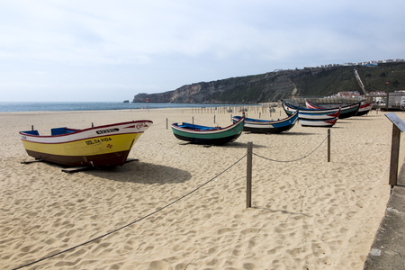 boats standing on a sandy beach in Nazare, Portugalのeditorial素材