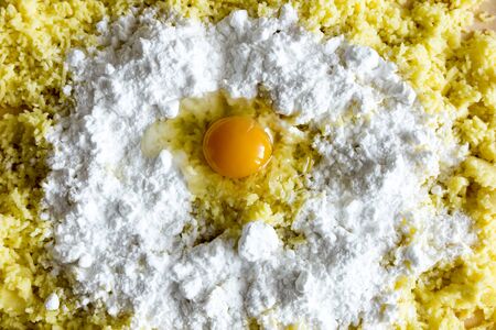 shredded potatoes, flour and broken egg on the board prepared for making dough for Silesian potato dumplingsの写真素材