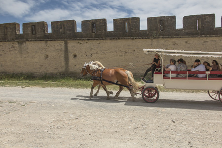 Carcassonne, France June 25, 2019: Tourists ride on a horse-drawn vehicle around Carcasson, a fortificated castle, a UNESCO World Heritage Site, Franceのeditorial素材