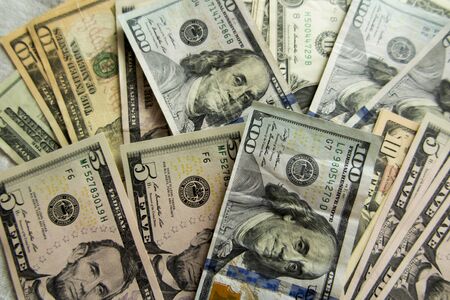 dollar bills of various denominations spread out on a flat surface as a background