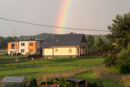 rainbow over a wooden house in a rural settingの写真素材