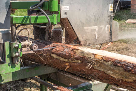 Mobile sawing equipment for logs in the open air. Rural landscape on a sunny day. Mobility and work...