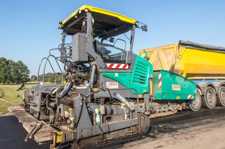 Kalety, Poland, October 5, 2021: Machine spreading the second layer of asphalt during the construction of a paved road on a dirt roadのeditorial素材