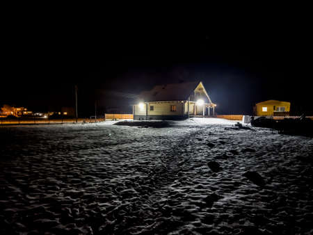 a log house on a winter evening on a slightly snow-covered building plotの写真素材