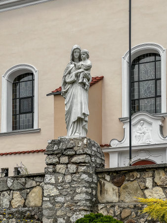 Stone figure of Mary with Jesus in front of the Church of the Assumption of the Blessed Virgin Mary (Sanctuary of the Motherhood of the Blessed Virgin Mary) in Zbroslawice, Poland.のeditorial素材