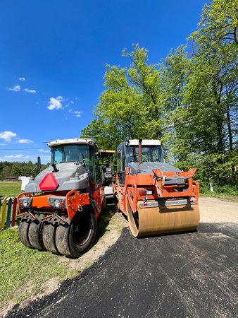 Road rollers left on the side of a road under construction.