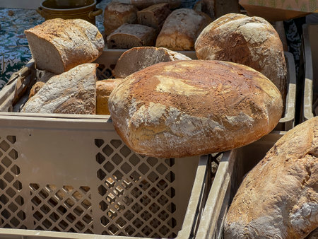 Loaves of bread lying in plastic crates ready to be cut, tasted and sold.