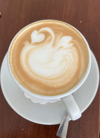 A cup of coffee with milk prepared so that a decorative pattern is created on the surface of the coffee.の写真素材