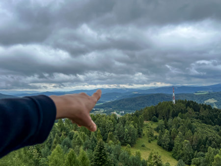 A hand with an outstretched finger pointing in a mountainous area.の写真素材