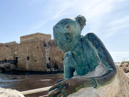 A statue of a woman lying on a rock in front of the castle in Paphos Harbor, Cyprus.の写真素材