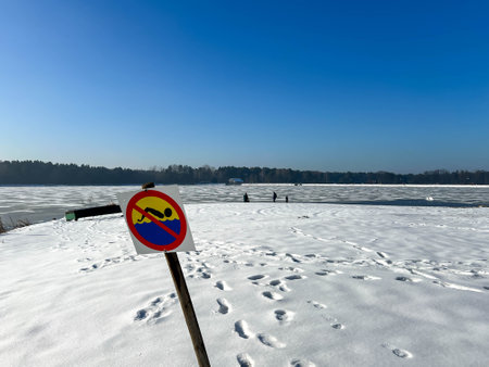 Sign prohibiting swimming by a frozen, snow-covered pond.の写真素材