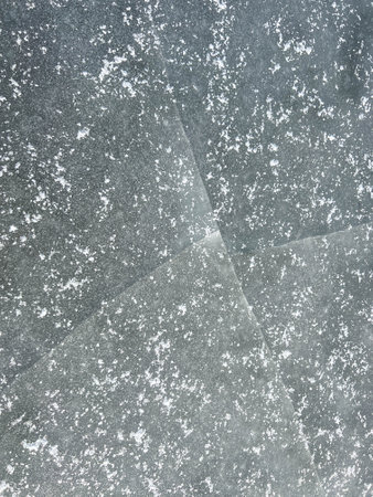 A crack in the ice sheet on a pond lightly covered with snow.