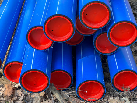 Blue plastic pipes with red caps stored ready to be dug into the ground.の写真素材